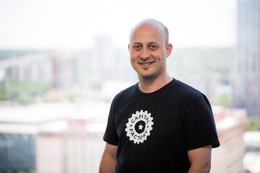 Joshua Baer in a Capital Factory t-shirt with the Austin skyline behind him